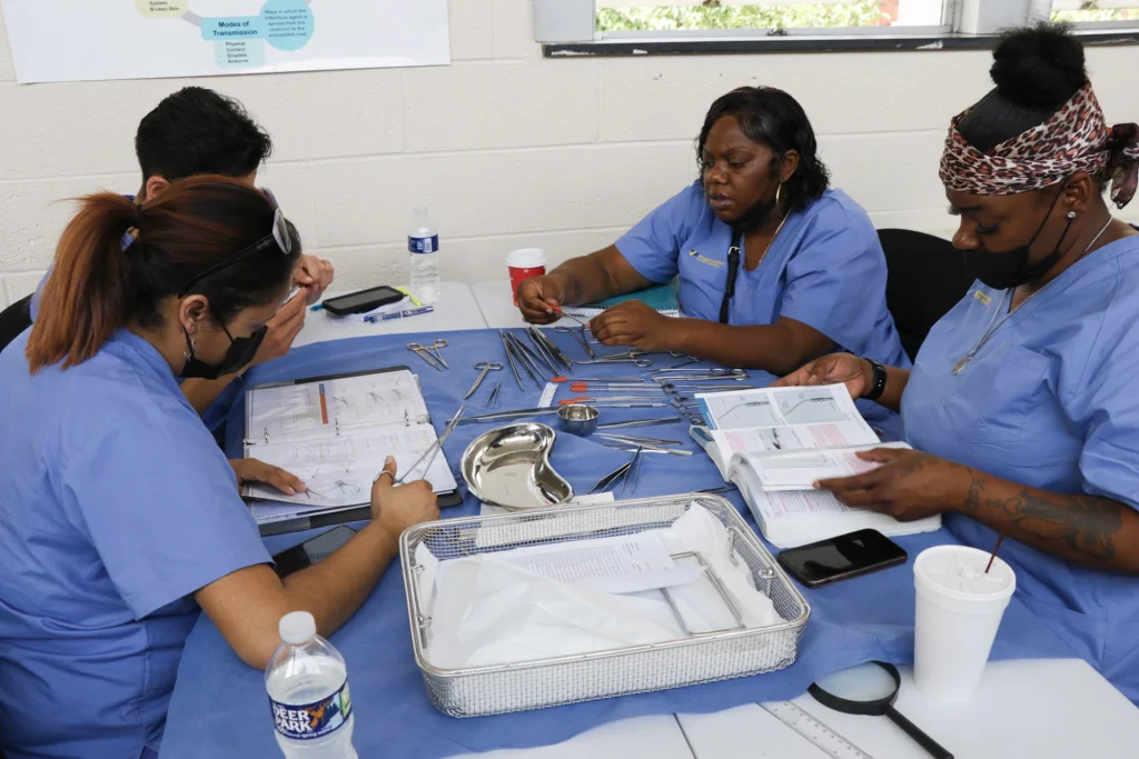 PTTI sterile processing technician students studying surgical instruments in a group session. 