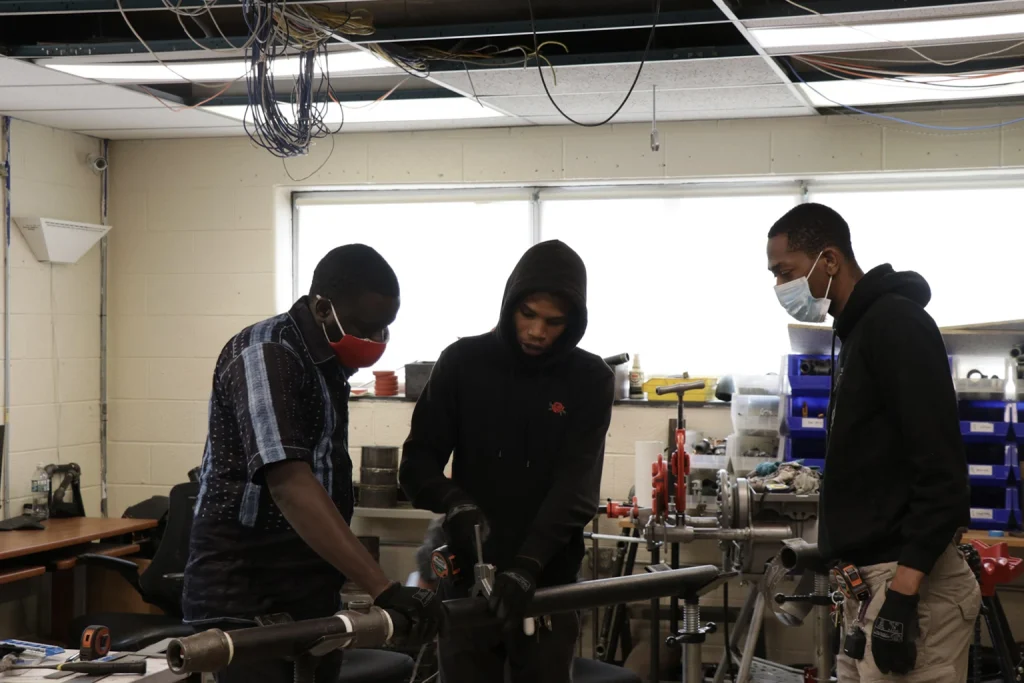 Students receiving hands-on pipe trade training at PTTI work lab 