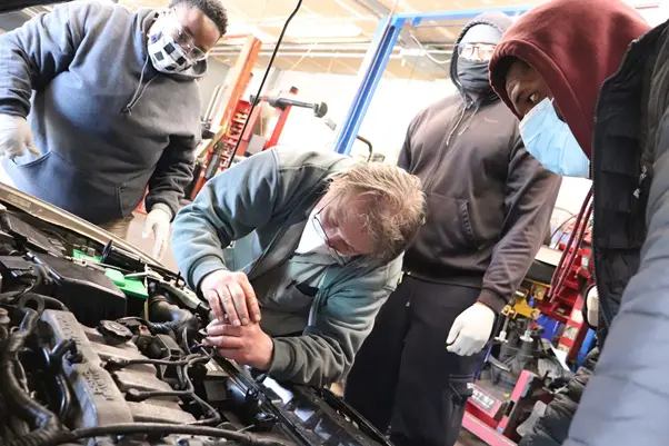 Students in a workshop learn how to mend car engines