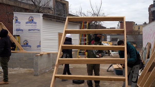 Construction workers carrying a wooden frame at a job site