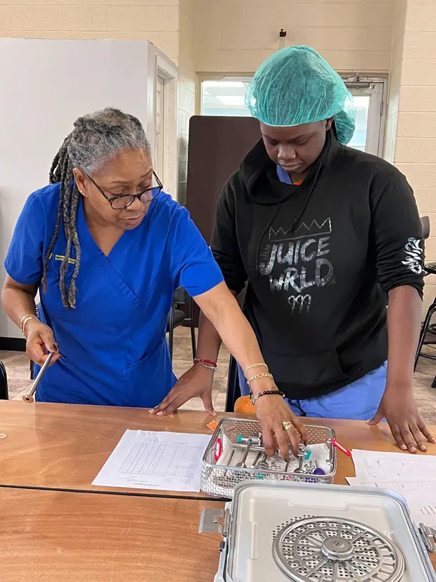 Mentor teaching sterile processing techniques to students during hands-on training at PTTI