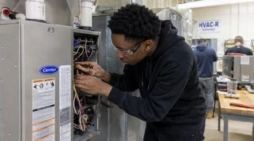 HVAC student practicing refrigerant handling for EPA 608 certification in a Philadelphia HVAC training lab
